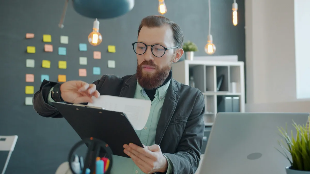 Un hombre con anteojos revisando un documento en un escritorio