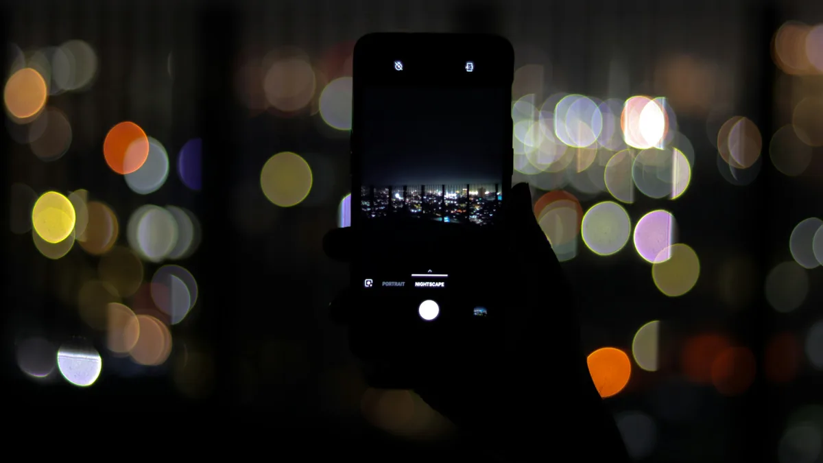 Un teléfono sostenido de noche contra luces desenfocadas de colores
